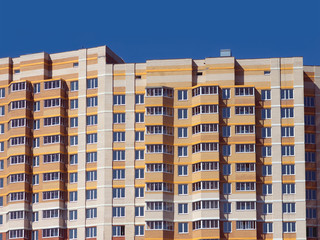 Top section of multi-storey modern building constructed from bricks over clear blue sky