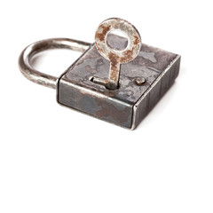 Vintage design closed iron padlock. key in hole. macro view, white background
