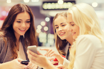 happy women with smartphones and tablet pc in mall