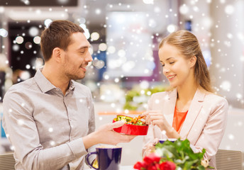 happy couple with present and flowers in mall