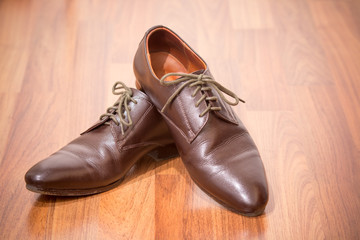 A pair of men's brown leather shoes on wooden floor