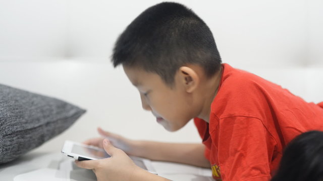 Asian boy playing tablet at home. 