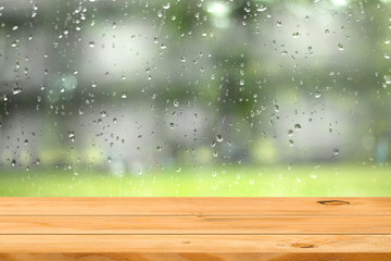 Empty wooden table over water drop on window garden background. Ready for product display montage.