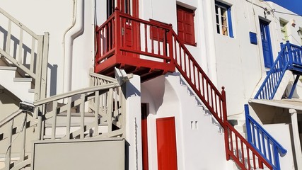Fototapeta premium Treppe in grau, Treppe in rot, Terppe in blau, nichts als Treppen vor weiß getünchten Häusern