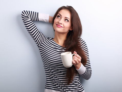 Casual attractive thinking woman holding cup of tea and pensive