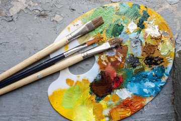 Brushes and colorful abstract oil colors paiters pallet, on grunge background