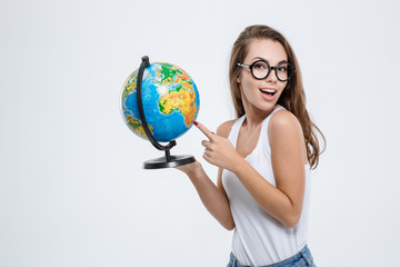 Fototapeta premium Woman pointing finger on globe and looking at camera