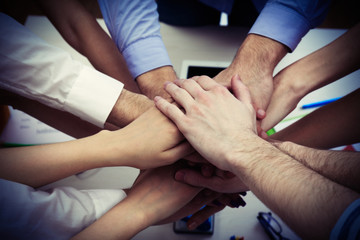 United hands of business team on workspace background top view