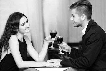 Young couple with wine at restaurant, black and white retro stylization