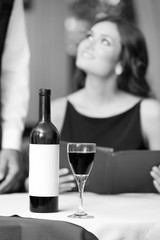 Portrait of beautiful woman with wine card at restaurant, black and white retro stylization