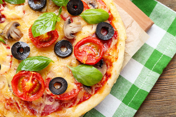 Tasty pizza with vegetables and basil on table close up