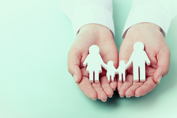 Female hands holding toy family on color background