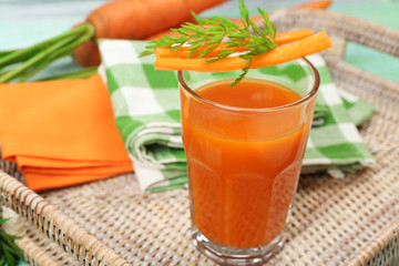 Glass of carrot juice with vegetable slices on table close up
