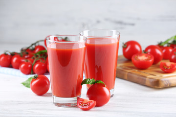 Glasses of tomato juice with vegetables on wooden table close up