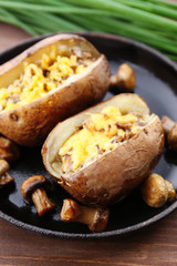 Baked potatoes with cheese and mushrooms on table close up