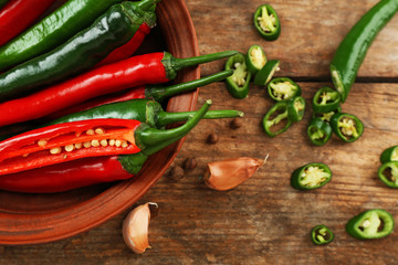 Hot peppers with spices on wooden table close up