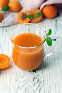 Cup of apricot juice and fresh fruits on table close up