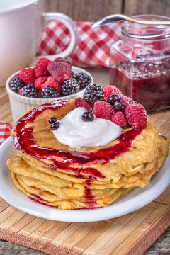 Pancakes with cream, raspberries and blackberries on the table