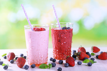 Glasses of berry smoothie on wooden table on blurred background