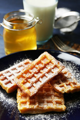 Sweet homemade waffles on plate, on dark wooden background