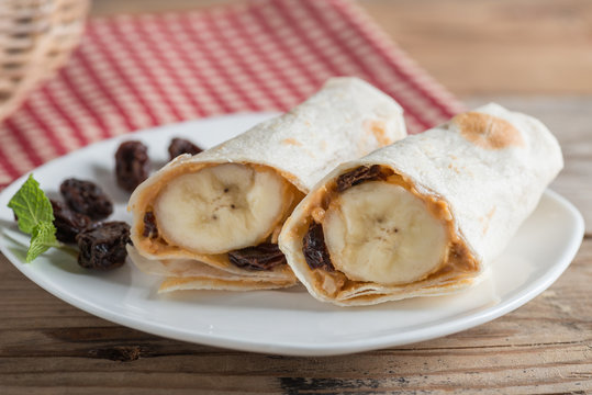 Fototapeta Slice tortilla wrap with peanut butter, raisin and banana.