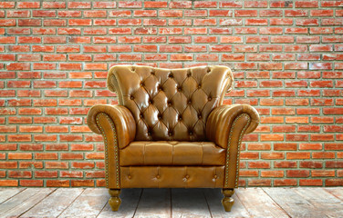 Vintage style  leather chair with wooden floor and brick wall.