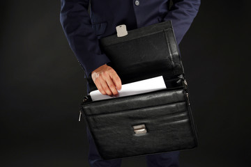 Elegant man in suit with briefcase on dark background