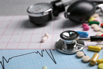 Blood pressure meter, pills and stethoscope, on grey background