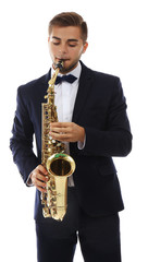 Fototapeta premium Young male musician playing golden brass saxophone in formal suit and bow tie, isolated on white background