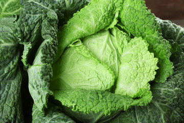 Savoy cabbage in wicker basket on wooden background, close up