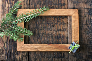 Wooden frame on a wooden board with a fir branches.