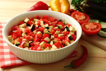 Ratatouille before cooking and ingredients, on wooden background