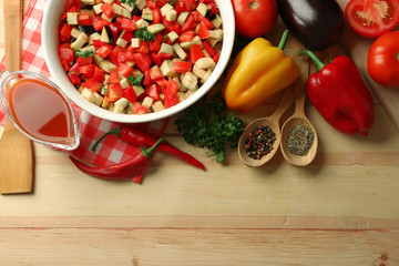 Ratatouille before cooking and ingredients, on wooden background