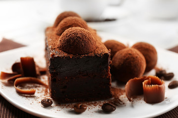 Slice of chocolate cake with a truffle on plate closeup