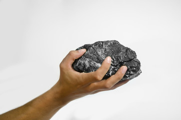 Male hand holding a lump of charcoal over white background