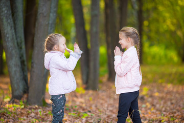 Little adorable girls playing in beautiful autumn park outdoor