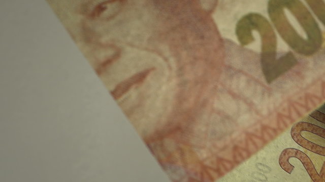 An extreme close up pan of a pile of randomly scattered south african rand banknotes