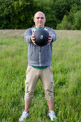 Fototapeta premium Mann trainiert mit 3 Kilo Medizinball im Freien