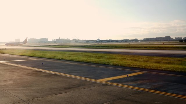 Airplane on runway exits frame through lensflare, 4K