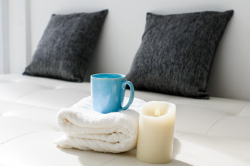 Cozy look, candle and coffee mug on white towel in living room