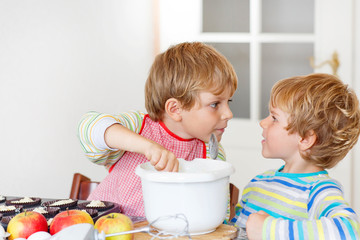 Two little kid boys baking apple cake indoors