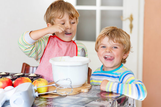 Two little kid boys baking apple cake indoors