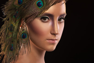 Beautiful girl with creative makeup and peacock feathers on black background
