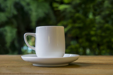 White coffe cup on the wooden table in the garden