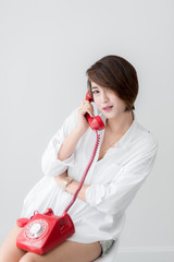 Fototapeta premium Smart Asian woman holding red vintage phone near window at home,