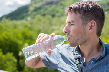 man drinking water from a bottle, outdoor with sunny day.