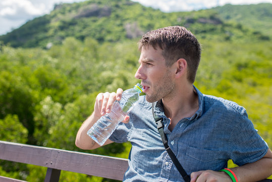 man drinking water from a bottle, outdoor with sunny day.