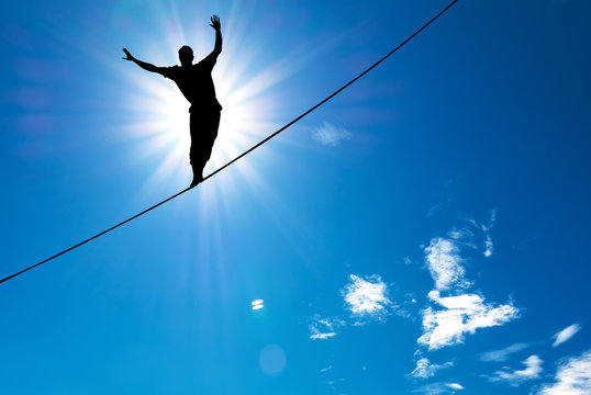 Silhouette of man balancing on the rope concept of risk taking