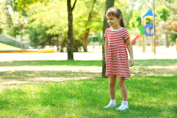 Little happy girl playing in park near the playground