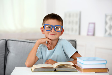 Little boy sitting on sofa with book, on home interior background